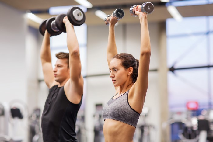 Man and Woman Lifting Dumbbells in Gym