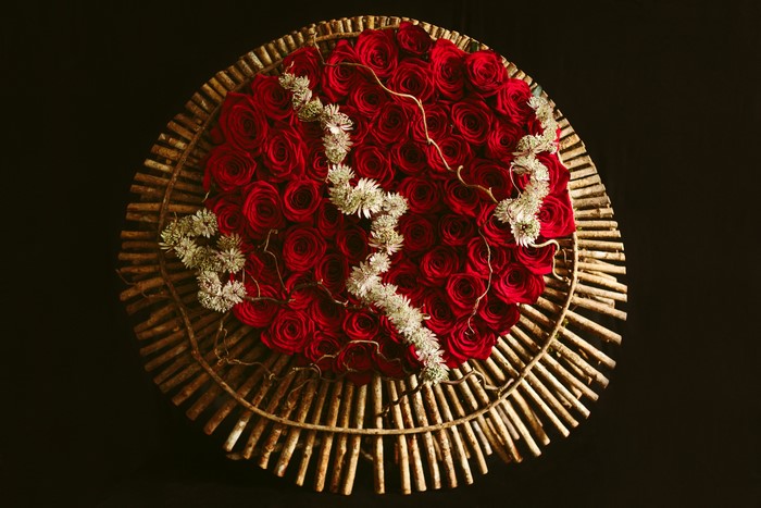Circular arrangement of red roses with white flowers and branches