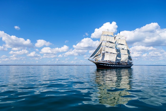 Tall Ship Sailing on a Blue Sea Under Clouds