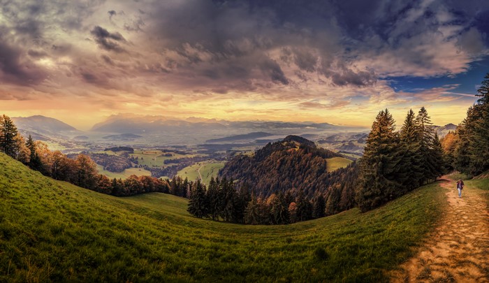 Panoramic view of Swiss Alps with a hiker on a trail