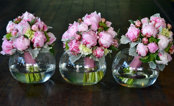 Three bouquets of pink peonies in glass vases