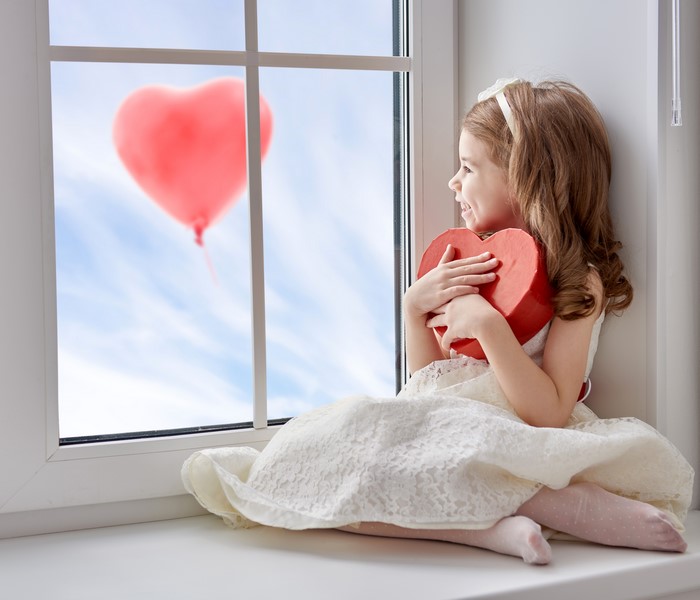 Girl with heart box looking at heart balloon