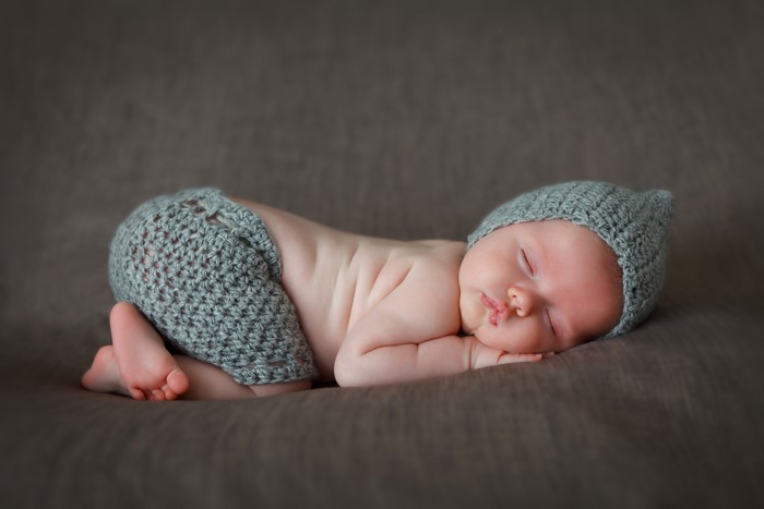 Newborn baby sleeping in a knitted hat and pants