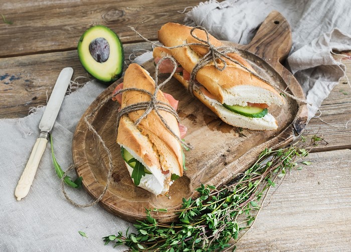 Sandwiches with prosciutto, cucumber, and avocado on a wooden board