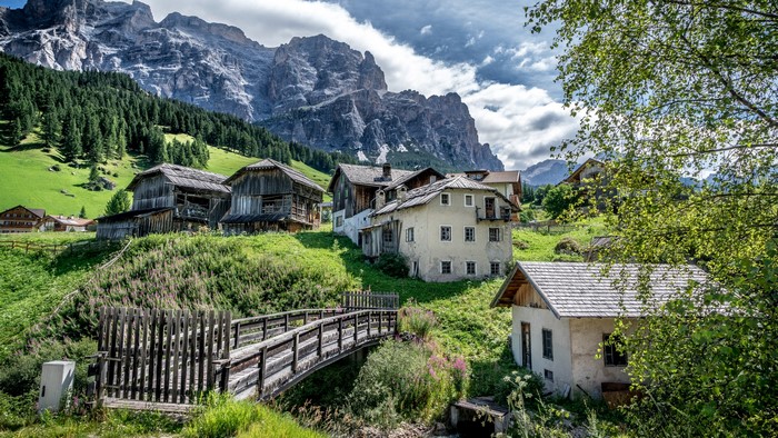 Houses and bridge in San Cassiano Alta Badia, Italy, with mountains