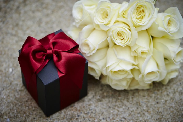 Gift box with red bow and white roses