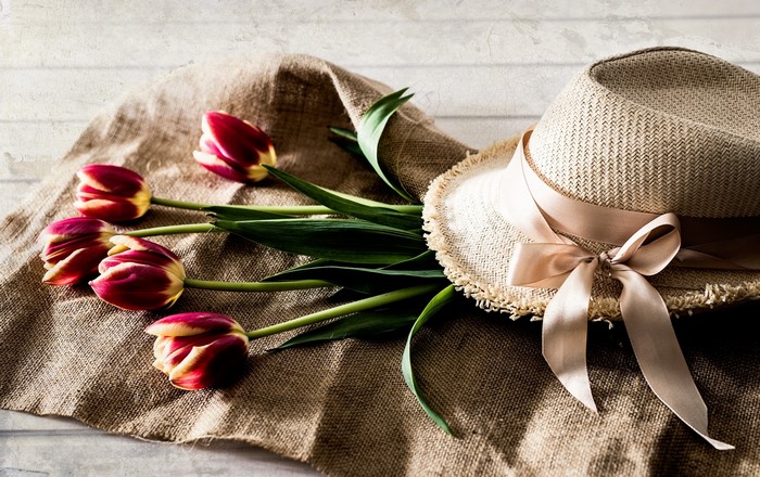 Straw hat with ribbon and tulips on burlap
