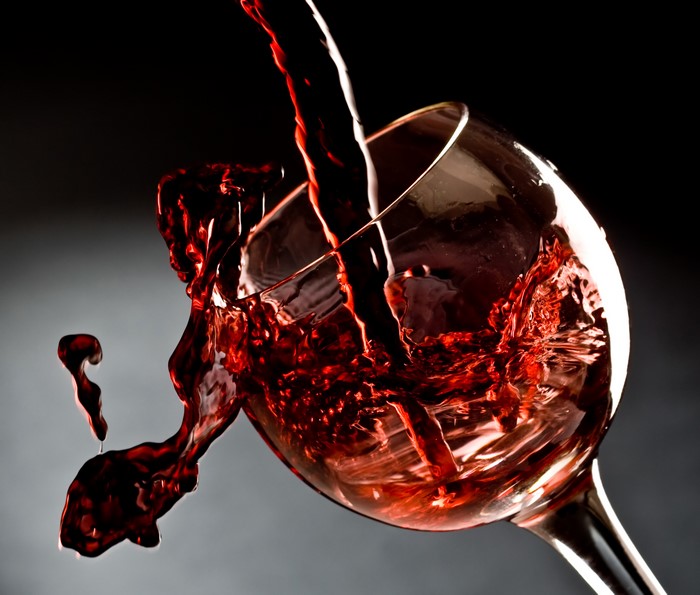 Red wine pouring into a glass, splashing