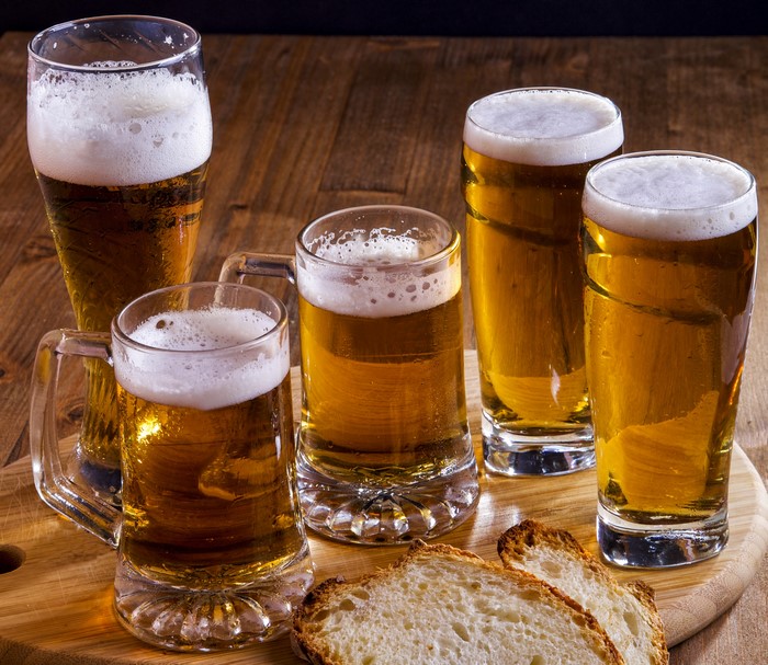 Four glasses of beer and bread on a wooden table