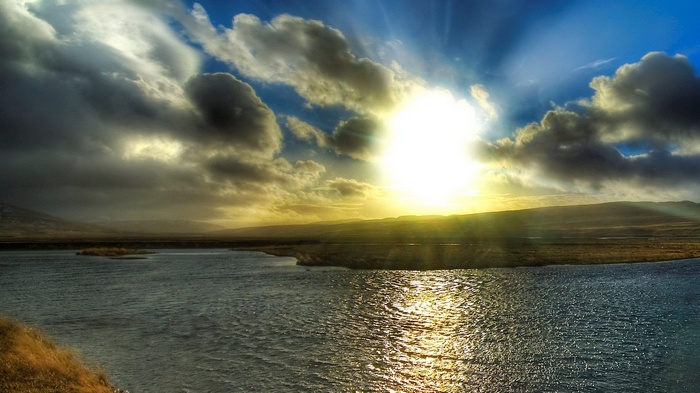 Sunbeams through clouds over a body of water