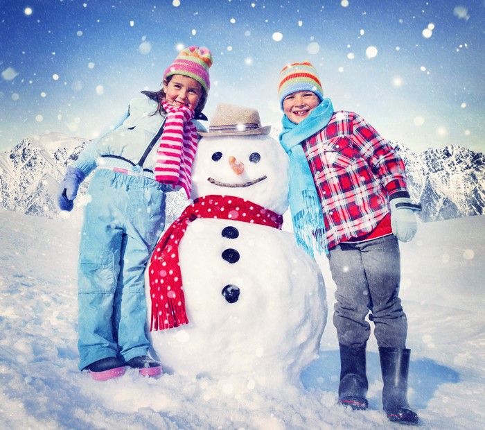 Two children with a snowman in winter