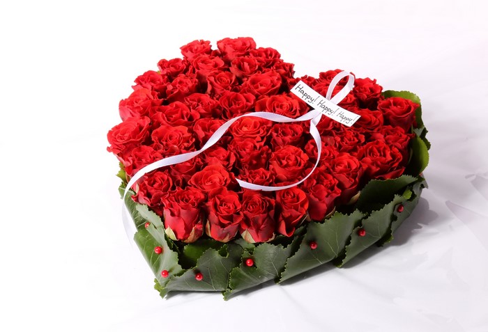 Heart-shaped bouquet of red roses with a white ribbon