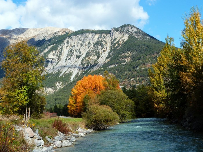 River flowing past trees with mountains in Val-des-Pres, France