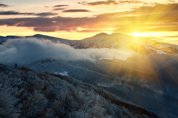 Sunrise over snow-covered mountains with clouds