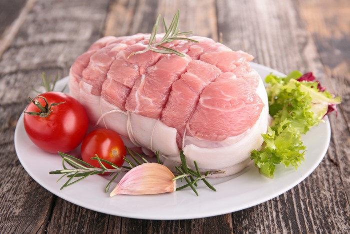 Raw meat roast with tomatoes, garlic, and rosemary