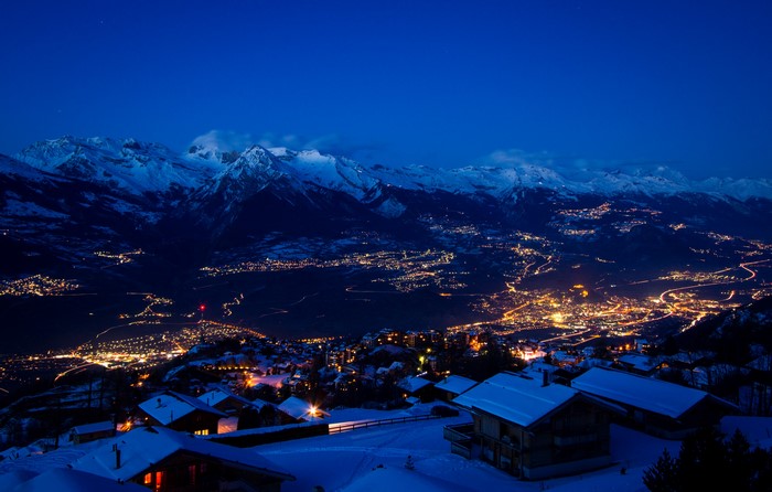 Snowy mountains and illuminated town at night in Switzerland