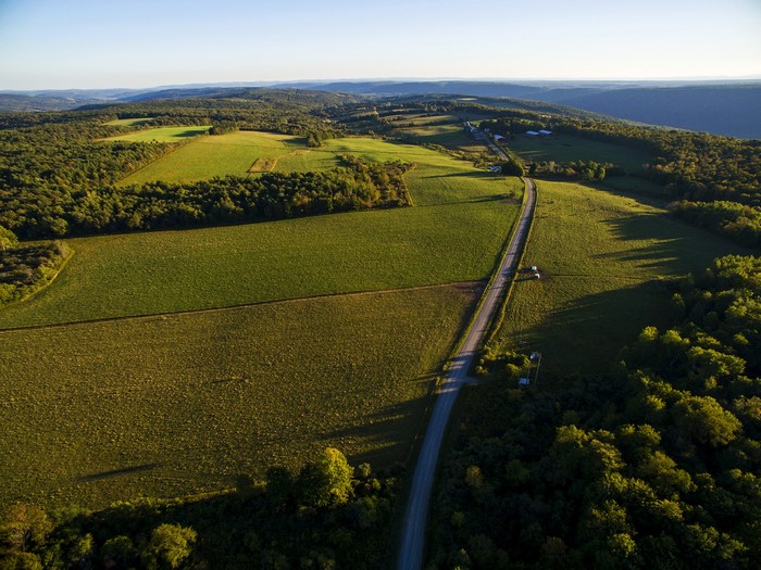 Aerial view of rolling hills with fields and a road