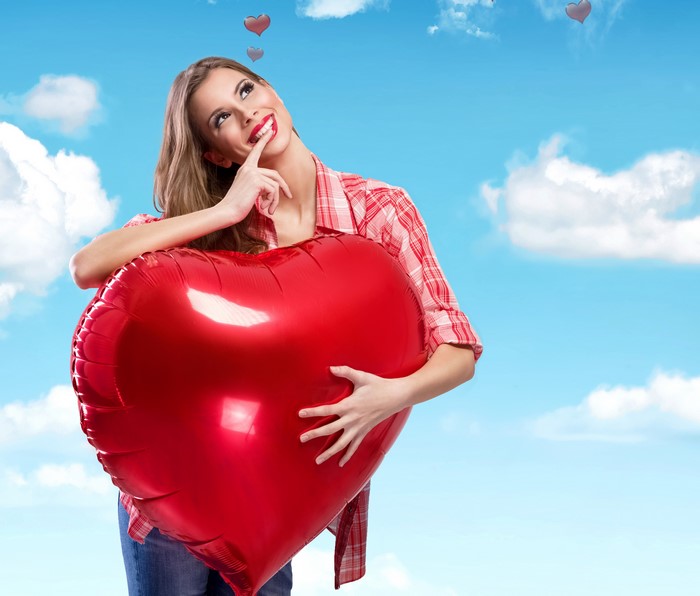 Woman holding a red heart balloon