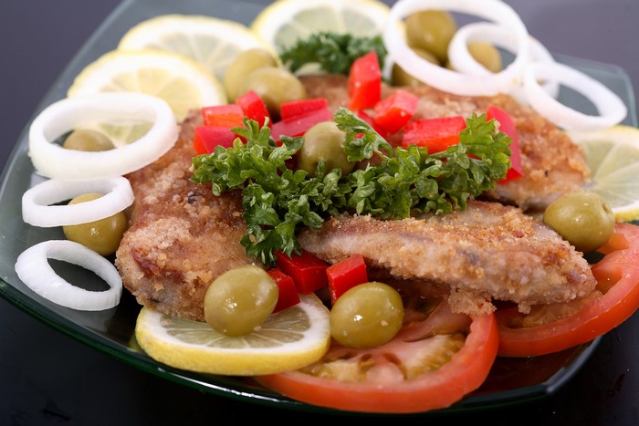 Fried fish with lemon, olives, and tomatoes