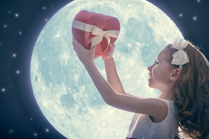 Girl holding a heart-shaped gift in front of the moon