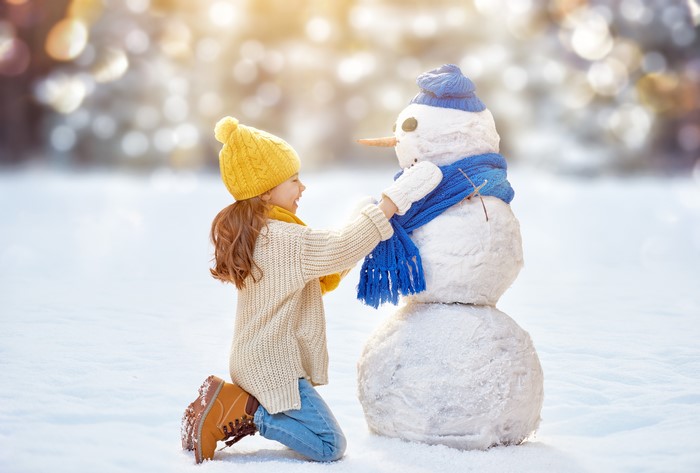 Girl in yellow hat building a snowman
