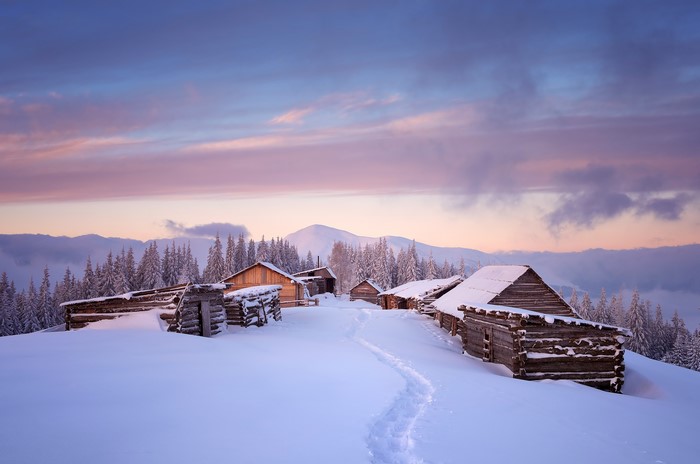 Winter village with snow-covered houses and mountains