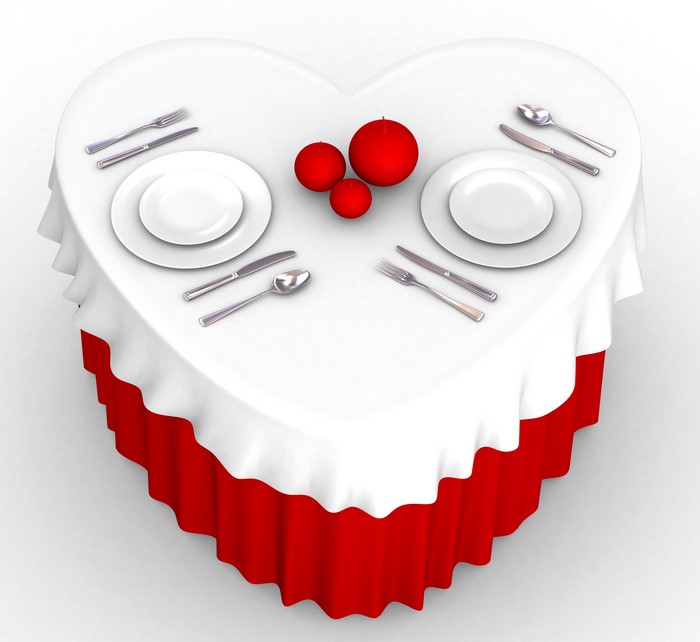 Heart-shaped table set for two with red candles