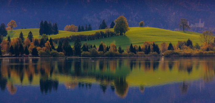 Lake reflection of autumn trees and Bavarian castle
