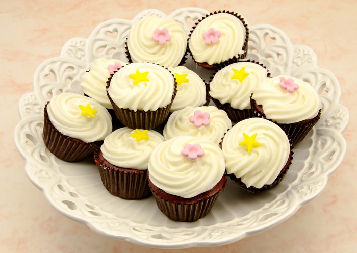 Many cupcakes with white frosting on a white plate
