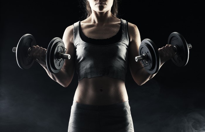 Woman performing dumbbell curls in a gym