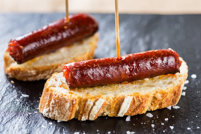 Two sausages on bread with toothpicks