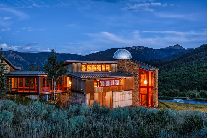 Modern house with observatory in mountains at dusk