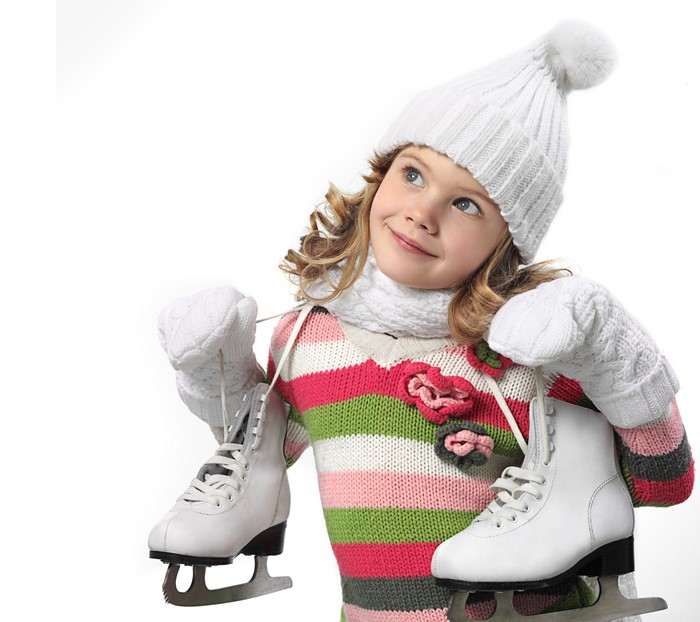 Girl in winter hat and sweater holding ice skates