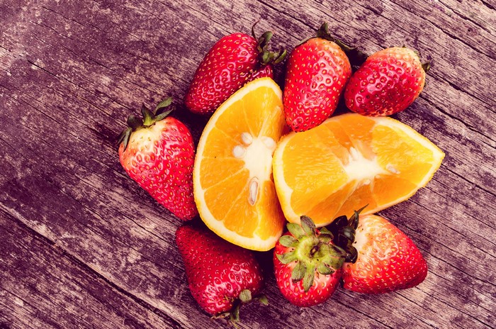 Strawberries and orange slices on a wooden table