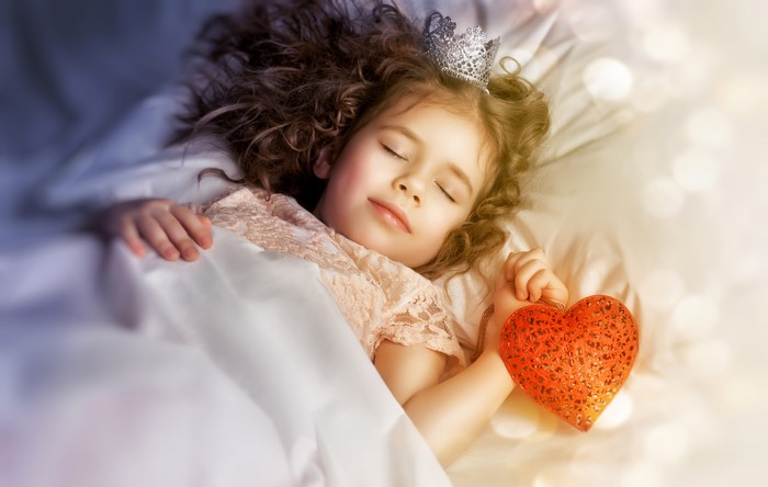 Little girl in crown sleeping with heart