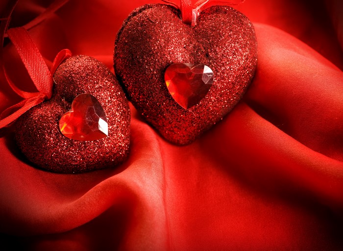 Two red glitter hearts with gems on red silk