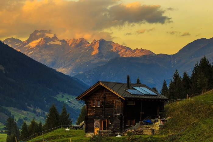 Wooden house with solar panels in the Swiss Alps at sunset