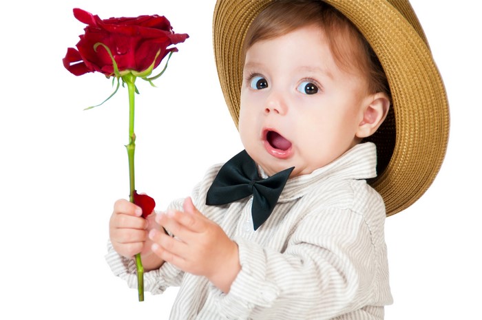 Baby boy in hat holding a red rose