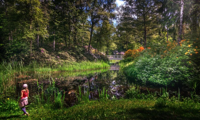 Girl by a pond in a park with a bridge