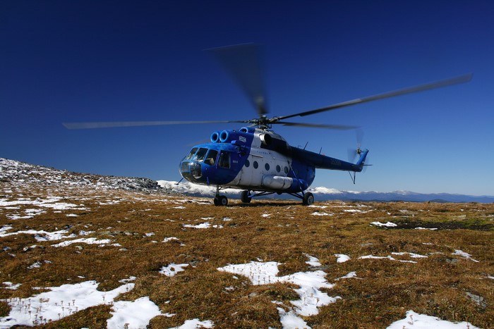 Mi-8 helicopter landing on a grassy mountain slope