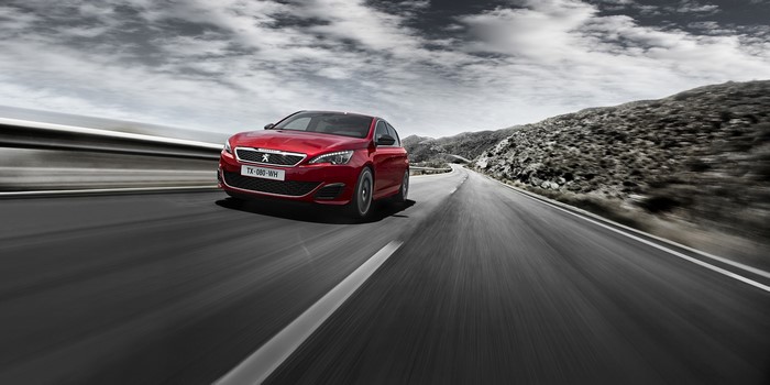 Red Peugeot 308 GTi driving on a road