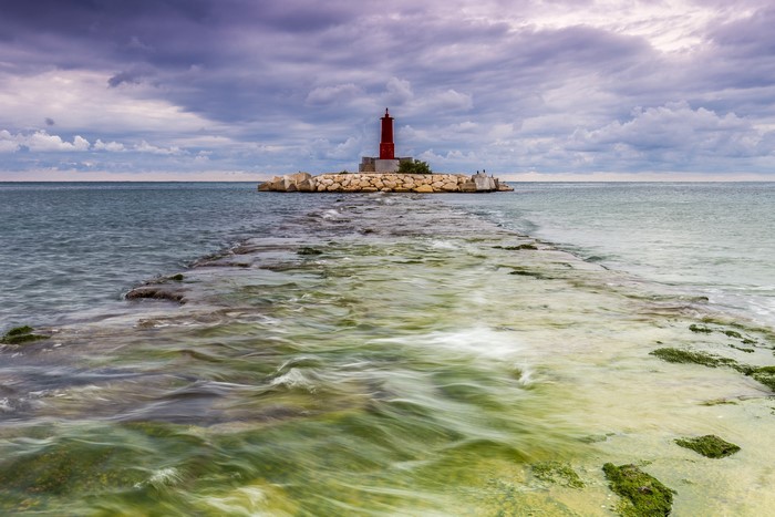 Red lighthouse on a rocky island in the sea