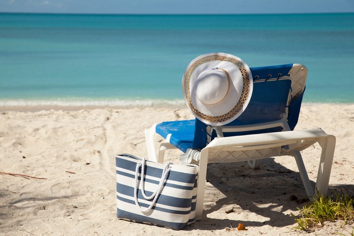 Beach scene with sunlounger, hat, and handbag