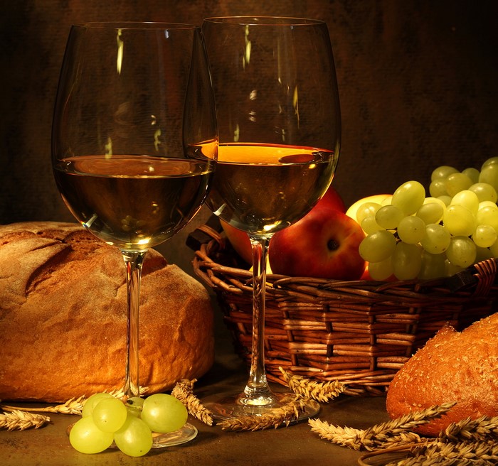 Two glasses of white wine with bread and grapes