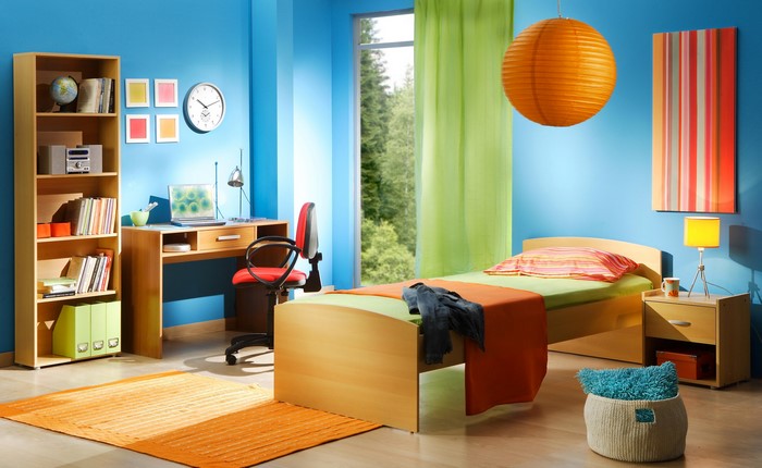 Modern bedroom with blue walls, desk, and bed