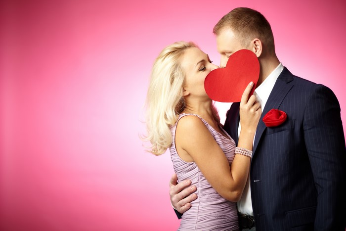 Couple kissing behind a red heart on Valentine's Day