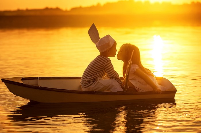 Two children in a boat kissing at sunset