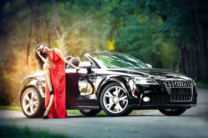 Woman in red dress with black Audi TT convertible