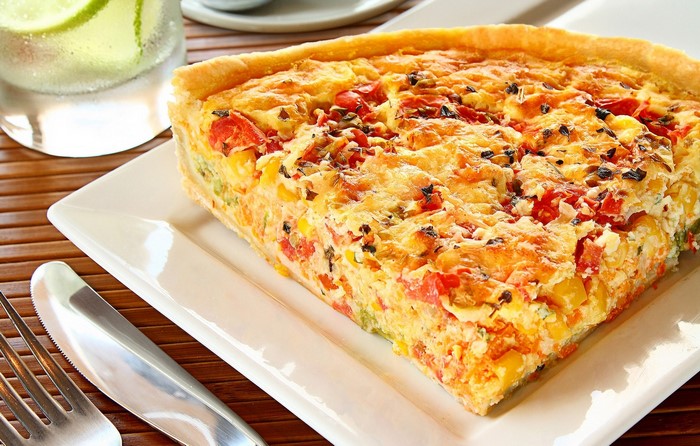 Slice of vegetable quiche on a white plate