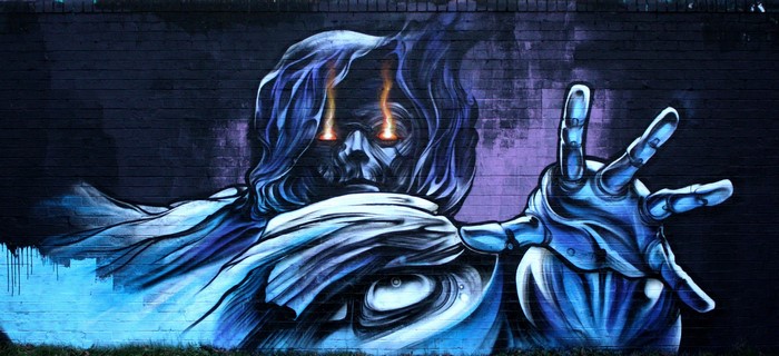 Graffiti of a ghostly figure with glowing eyes on a brick wall